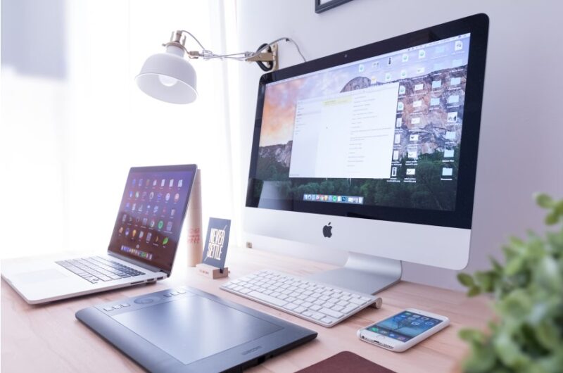 Desktop monitor, laptop, tablet, and smartphone all sitting on a desk.